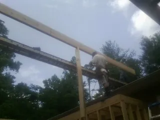 Carpenter setting a ridge beam over a new addition frame — Ice Dam Removal by Roofing Brothers in Perrinton