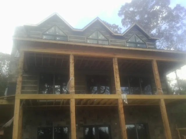 Dormers and porch framing on a large log home under construction — Roof Coating work by our crew in Perrinton