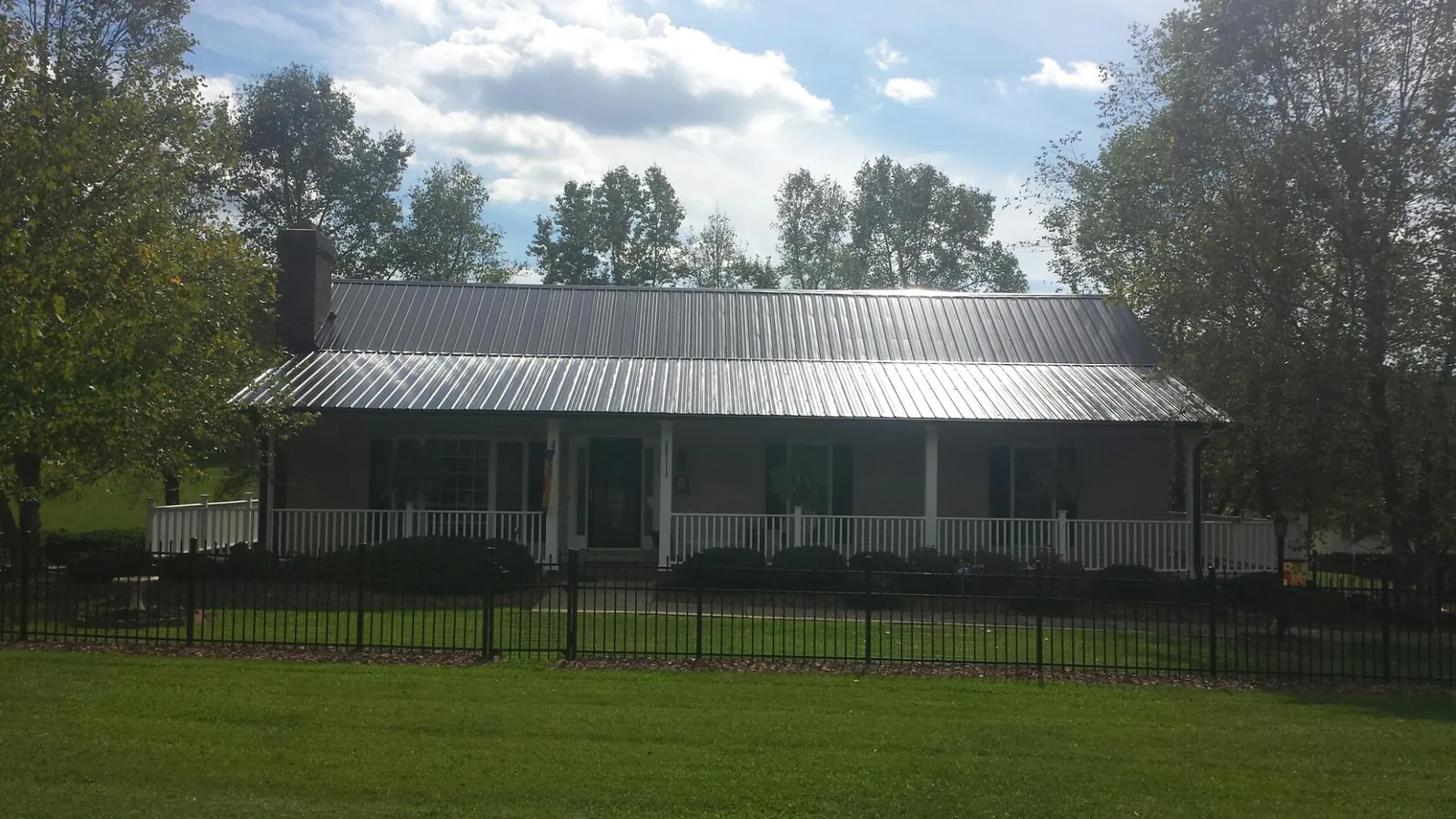 Gray metal roof on a brick ranch with a full width front porch — Gutter Guard Installation work by our crew in Perrinton