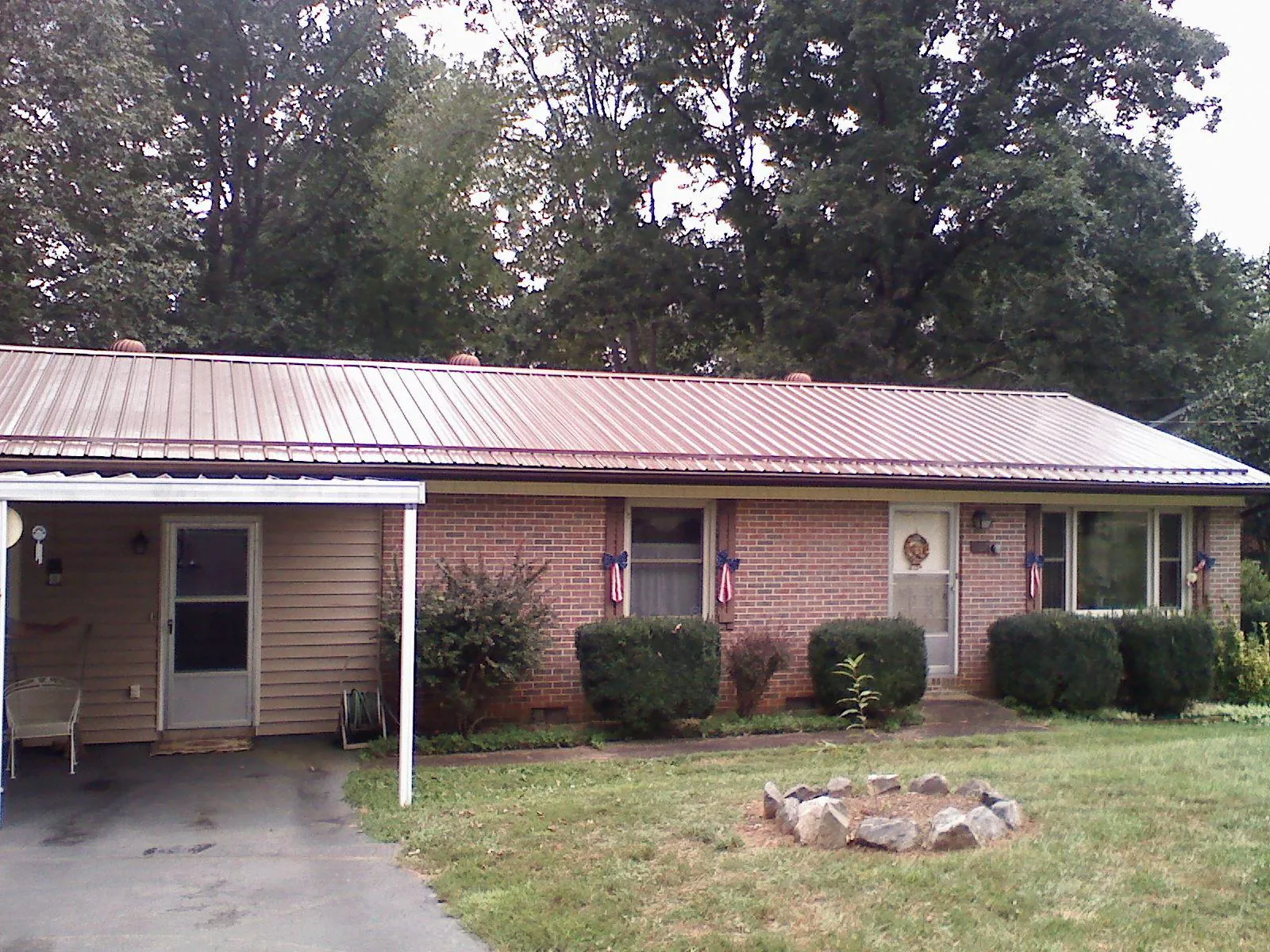 Bronze metal roof and carport on a brick ranch home — Roof Repair work by our crew in Perrinton