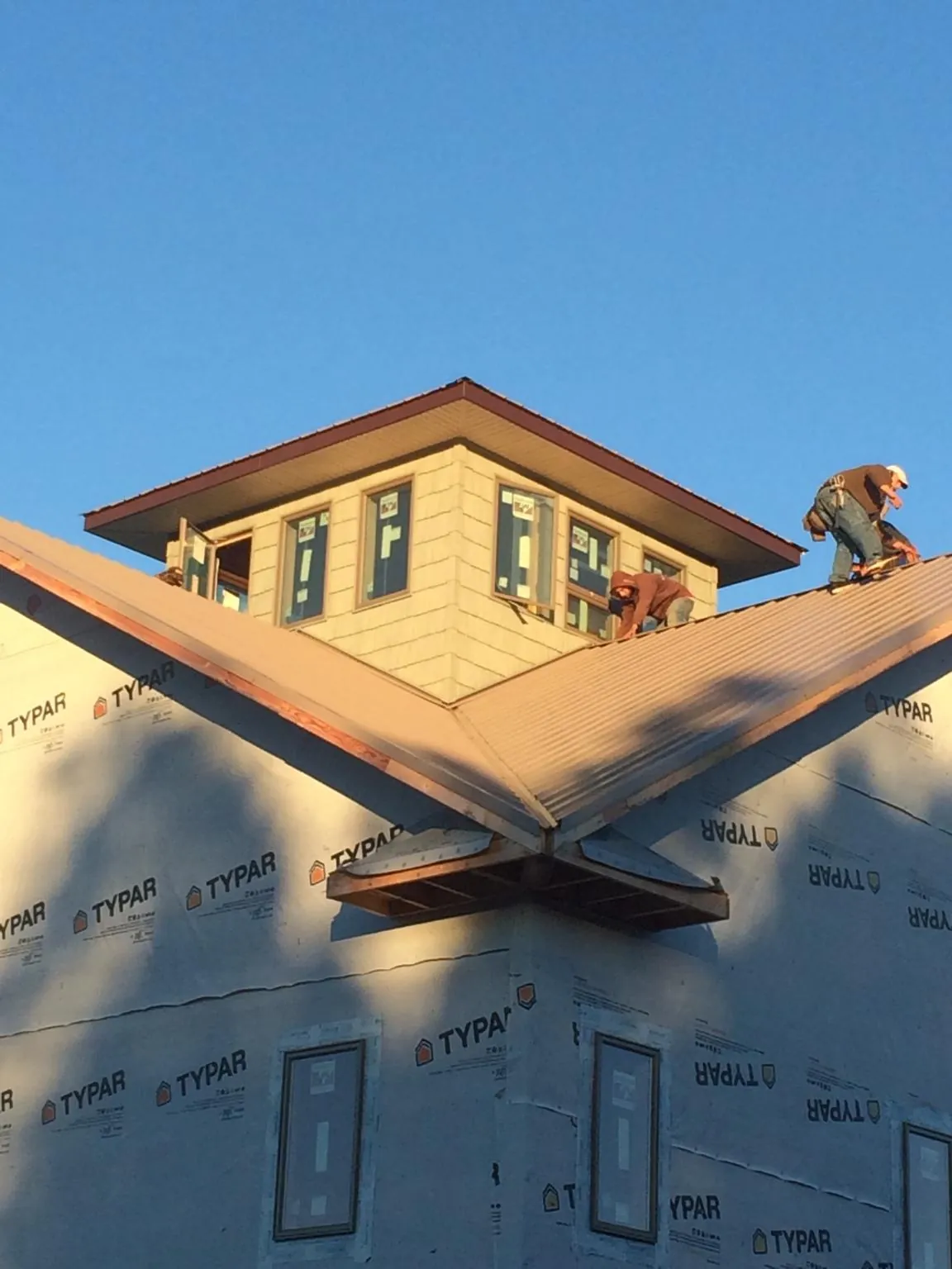 Roofers working around a rooftop cupola on a new metal roof at sunset — Roof Waterproofing in Perrinton by Roofing Brothers